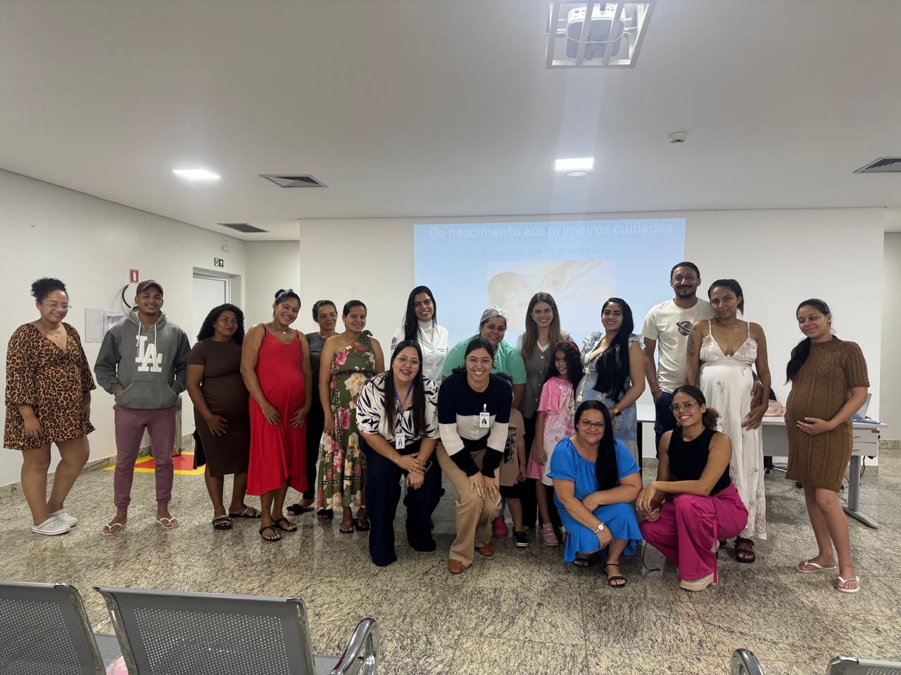 Curso para gestantes na Maternidade Augusta Bastos — Dra. Halana com gestantes, acompanhantes e a equipe da maternidade diante do telão da apresentação