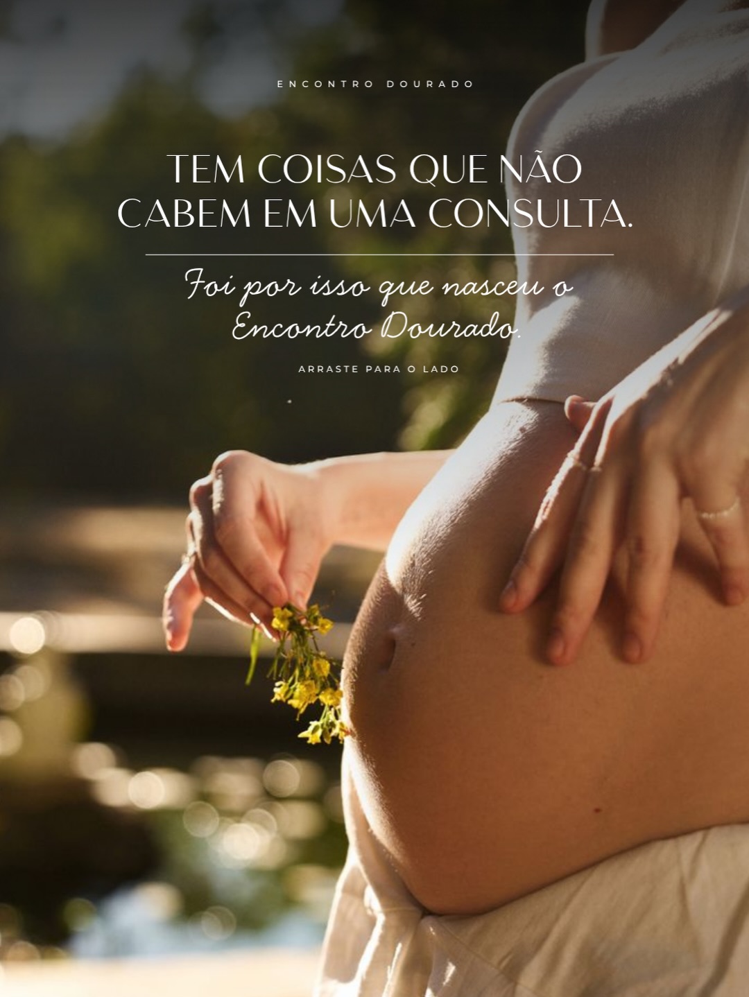 Encontro Dourado — gestante segurando flores do campo ao entardecer, com as mãos sobre a barriga